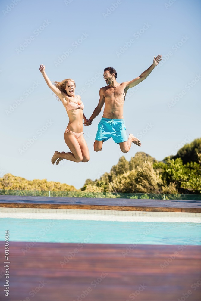 Fotografie Happy couple jumping in the pool