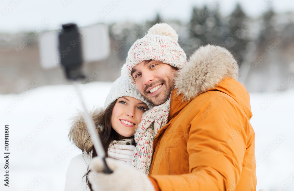 happy couple taking selfie by smartphone in winter
