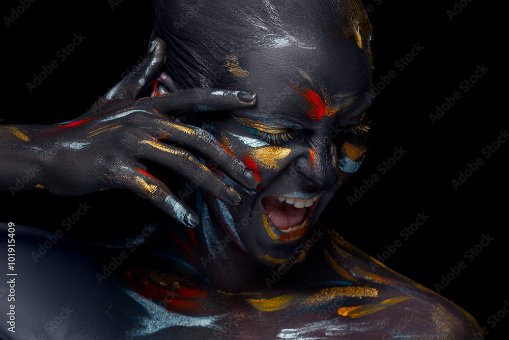 Fototapeta Portrait of a young woman who is posing covered with  black paint 