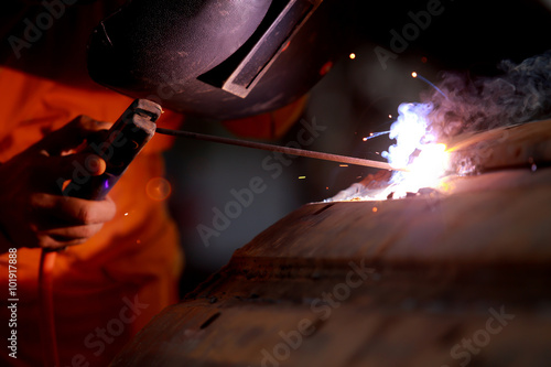 Close-up worker with protective mask welding metal.