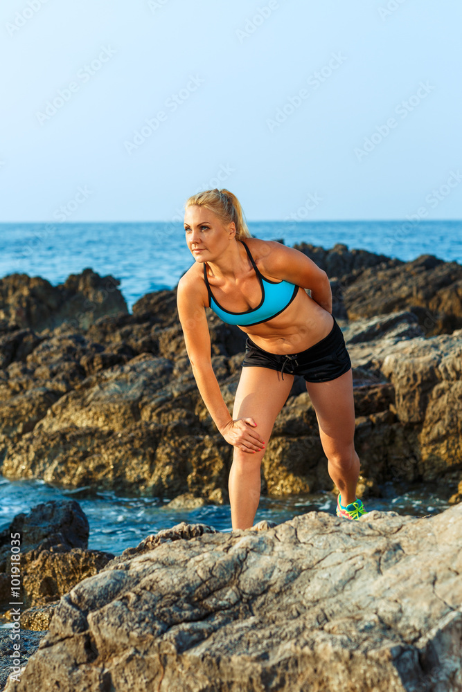 Athlete woman standing after sport exercising on the rocks by th Athlete woman standing after sport exercising on the rocks by th