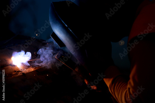 Close-up worker with protective mask welding metal.