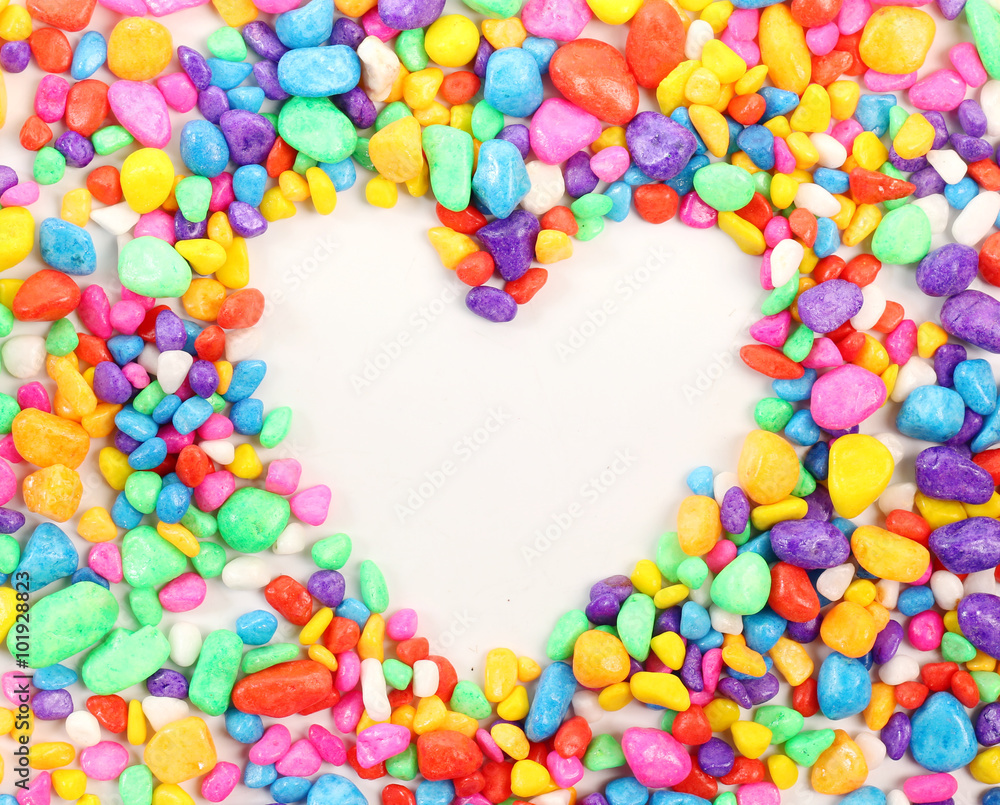 Colored stones arranged in a heart shape on white background. Colored stones arranged in a heart shape on white background.