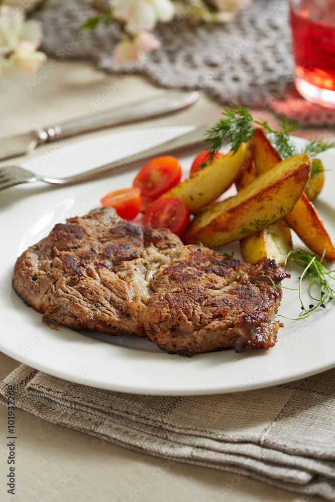 a piece of pork with sauteed potatoes and tomatoes a piece of pork with sauteed potatoes and tomatoes
