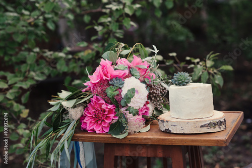 Wedding cake and bouquet of flowers  the bride s hands  baking  cake decoration