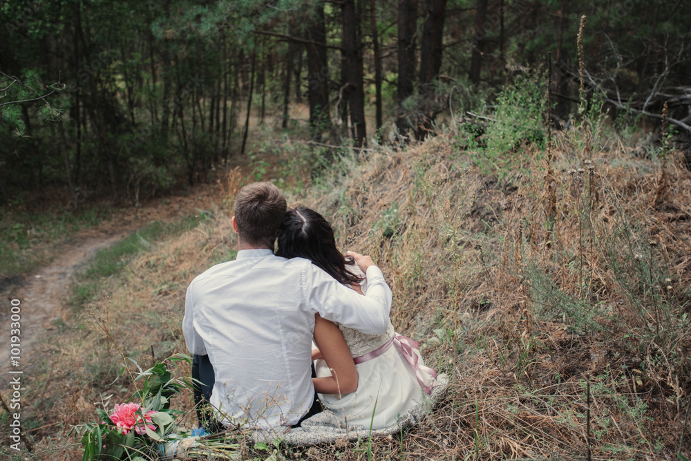Fototapeta premium Sweet couple sitting on a hill and looking at the autumn landscape