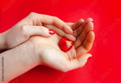 Decorative Heart in women's hands on red background