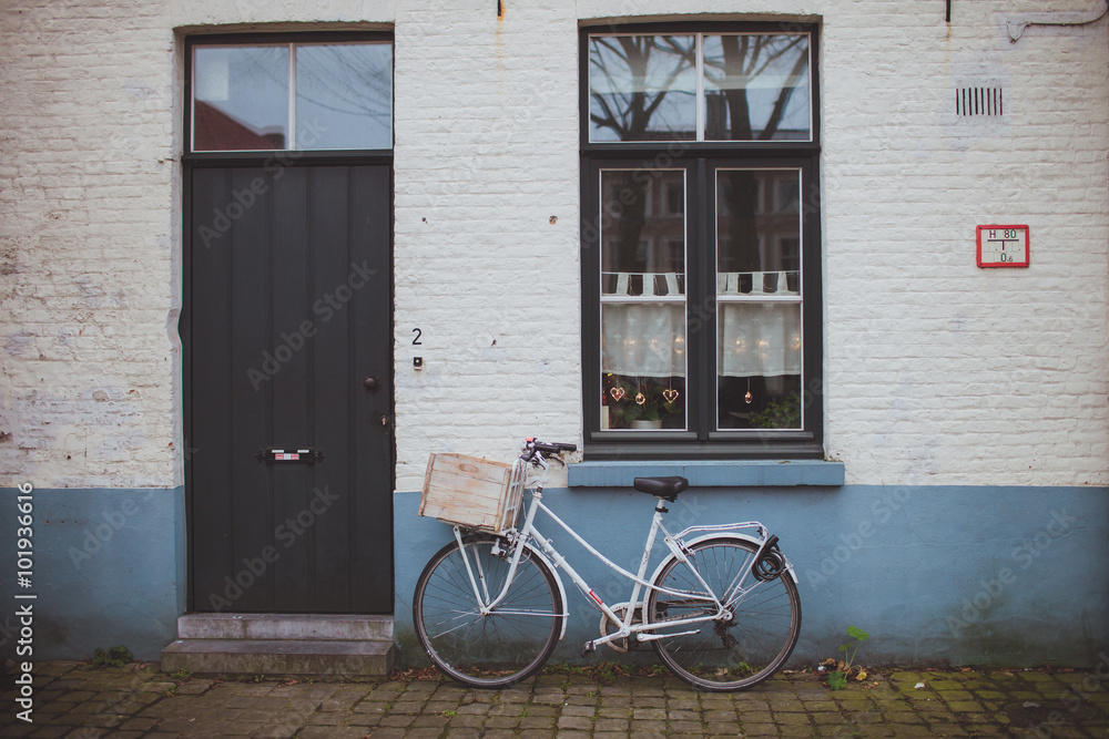 White bicycle standing near the brick facade of the house