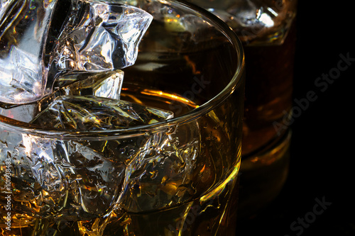 detail of whiskey glasses with ice cubes against dark background