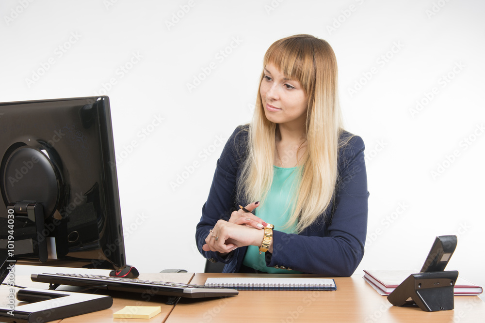 Business woman checks the time on a computer with a wristwatch Business woman checks the time on a computer with a wristwatch