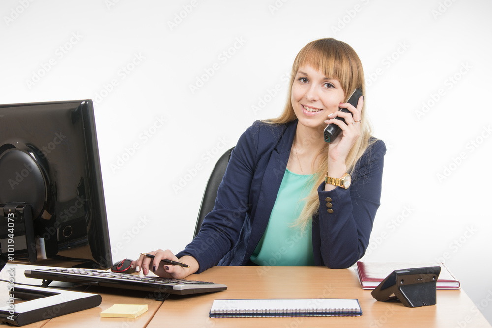 Business woman talking on the phone and working on the computer Business woman talking on the phone and working on the computer