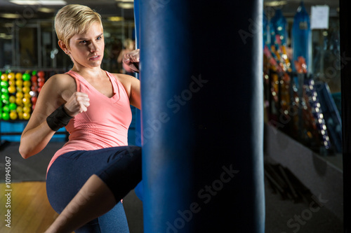Fitness in gym with punching body bag cute healthy thin fit young woman trains 