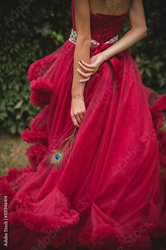 beautiful girl in a long dress in the garden. Peacock feather