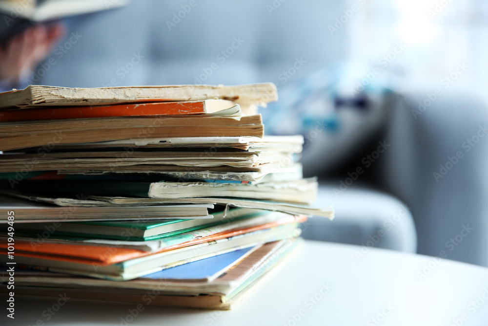 Pile of old books on white table in the room. Focus on books and blurred background Pile of old books on white table in the room. Focus on books and blurred background
