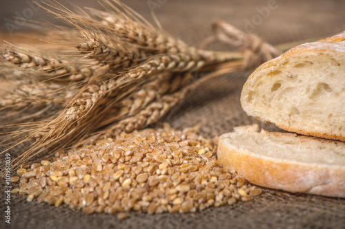 a ciabatta bread with wheat on stackcloth on a wooden rustic background photo