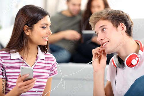 Teenager couple listening to music with mobile phone in living room