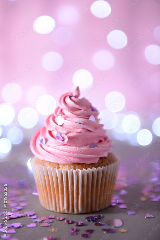 Cupcake with pink cream icing on a glitter background, close up Cupcake with pink cream icing on a glitter background, close up