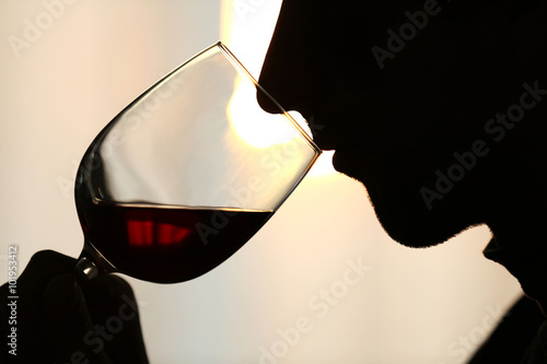 Foto Silhouette of man sniffing red wine in a glass, close up