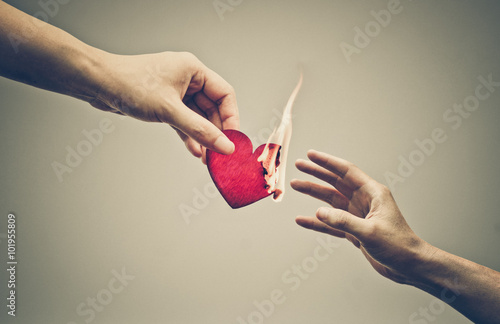 Female hand giving a heart on fire to male hand