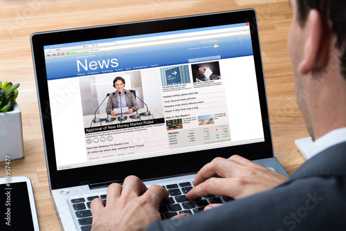 Businessman Reading News On Laptop At Desk photo