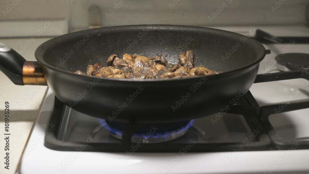 The mix of mushrooms is fried in a black pan The mix of mushrooms is fried in a black pan