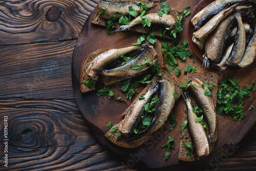 Sandwiches with sprats in a rustic wooden setting, above view