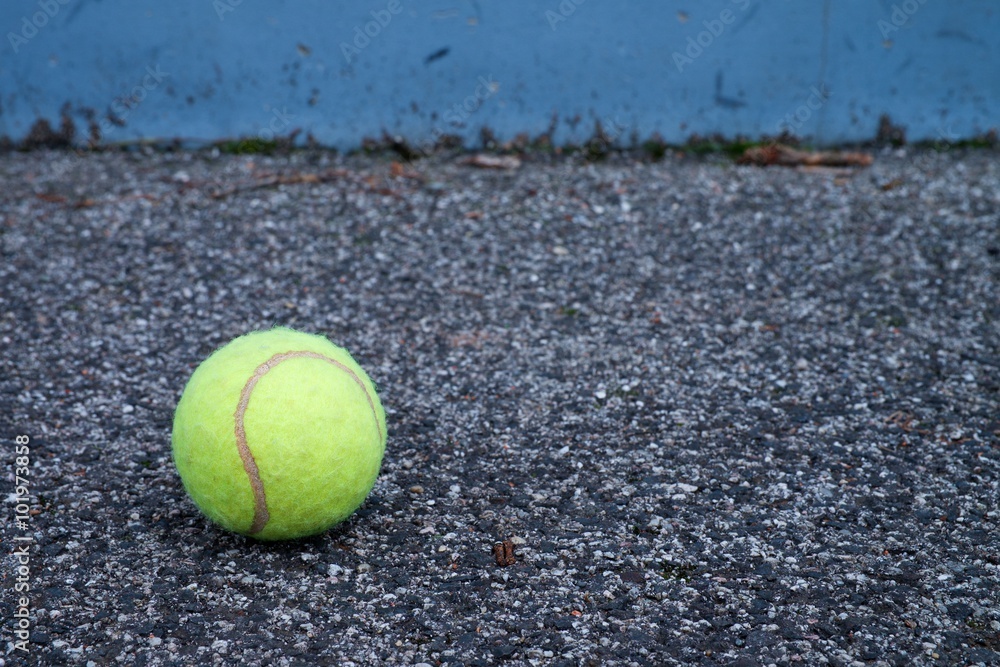 Ball beside tennis training wall. Empty training tennis court