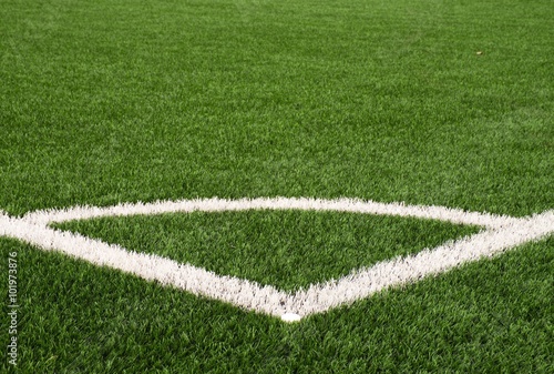 Football playground corner on artificial green turf ground with painted white line marks. Milled black rubber in basic.