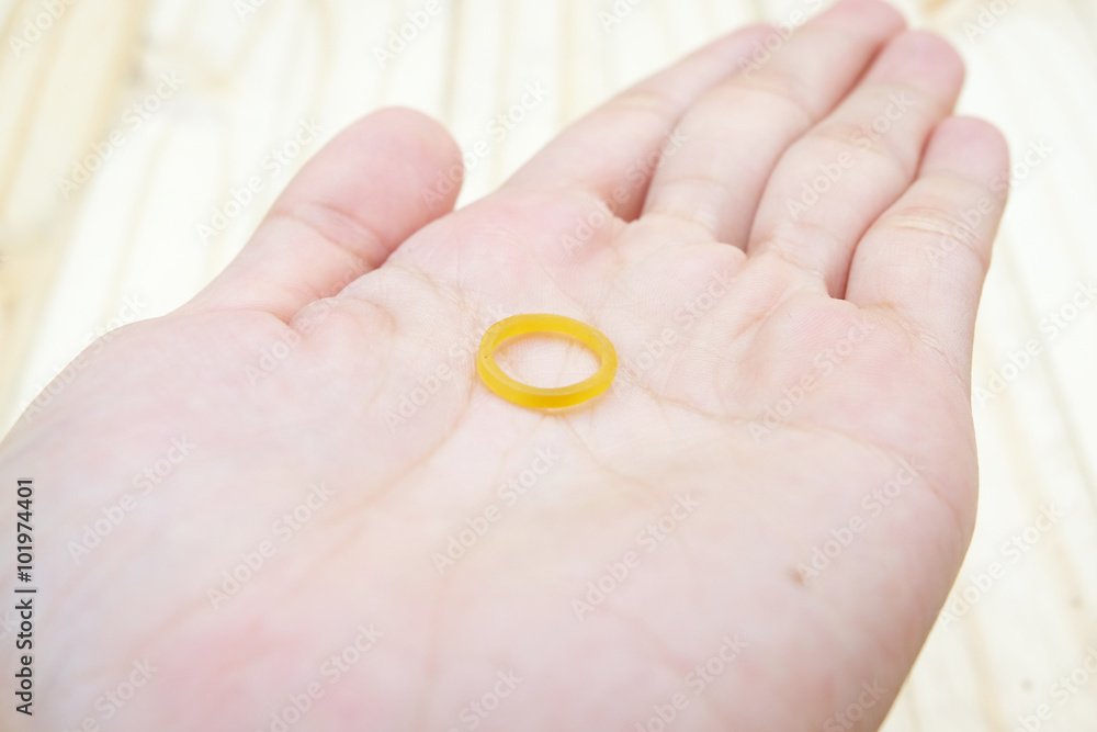 yellow elastic plastic band on hand with wood ground