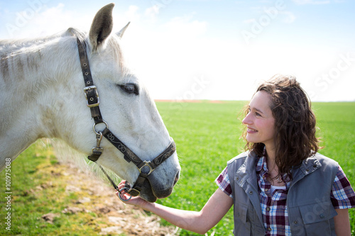 Young attractive farmer woman talking to horse