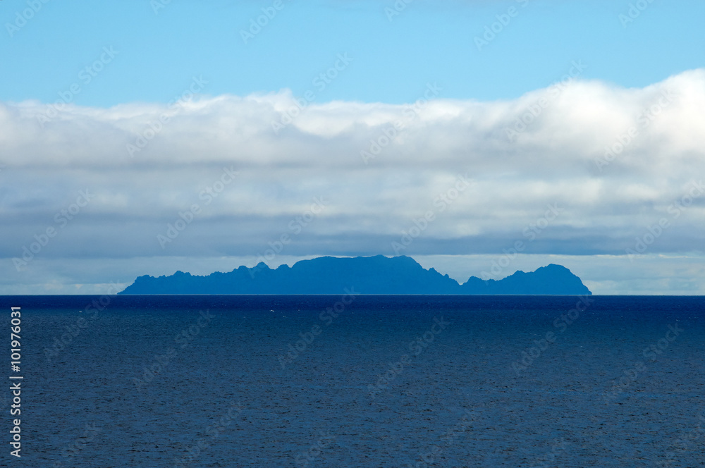 Seascape with blue sky and white clouds with island on horizon