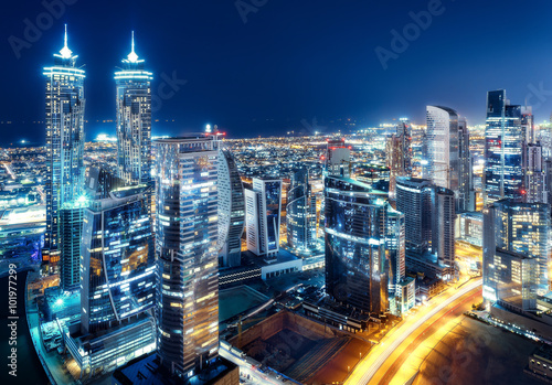 Scenic rooftop nighttime cityscape with illuminated modern architecture. Dubai downtown, United Arab Emirates.