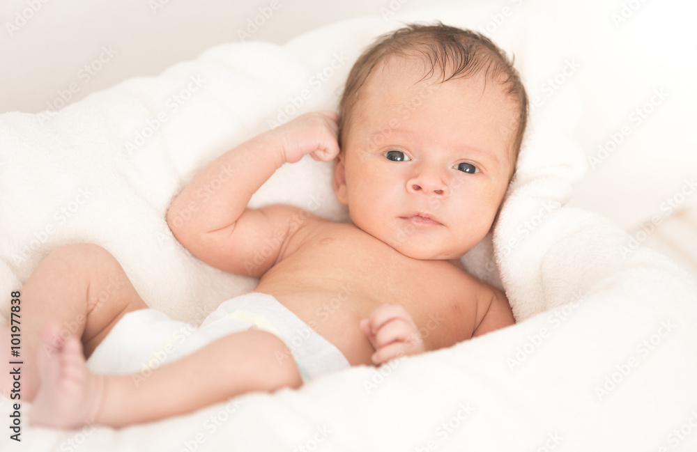 Smiling baby boy lying on soft beige blanket and cushion Smiling baby boy lying on soft beige blanket and cushion