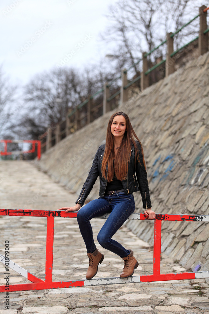 Beautiful brunette girl wearing leather jacket, blue jeans and boots Beautiful brunette girl wearing leather jacket, blue jeans and boots