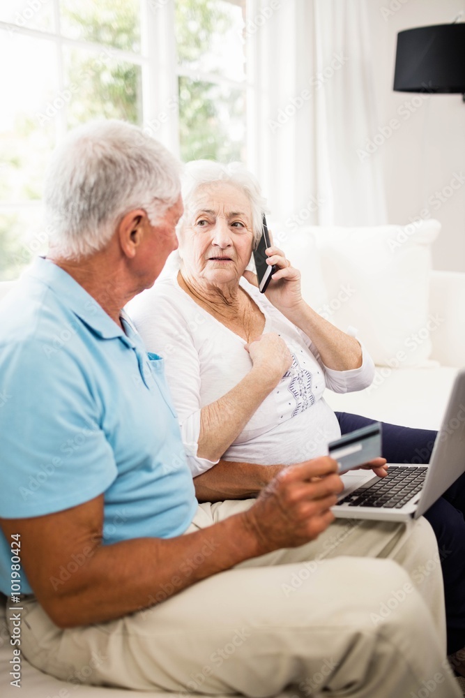 Fotografie Smiling senior couple using laptop and smartphone