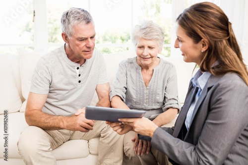 Businesswoman showing tablet to senior couple