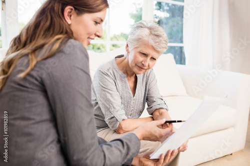 Smiling businesswoman showing documents to senior woman