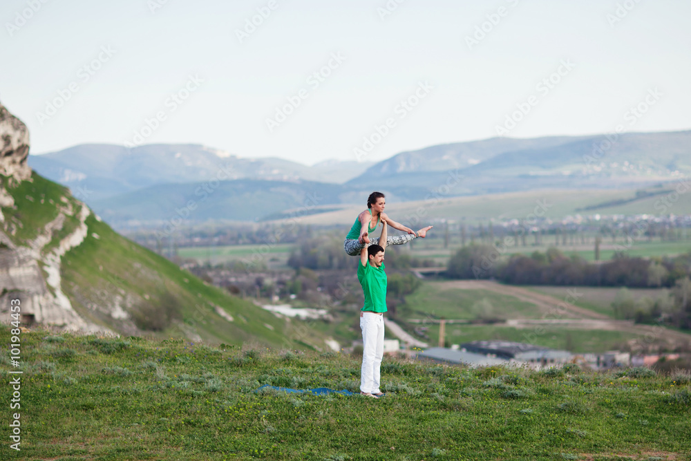 Acroyoga - Balancing on Feet. Couple practicing acroyoga in mountains at sunrise. Crimea