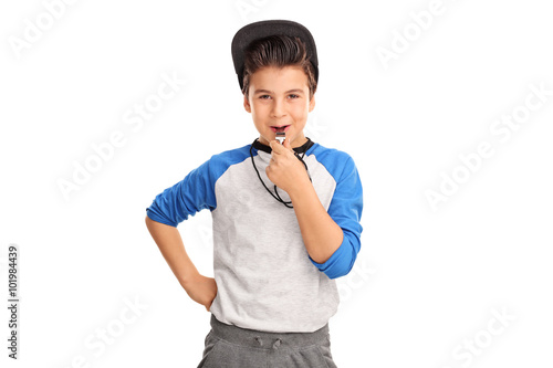 Cheerful boy in sportswear blowing a whistle