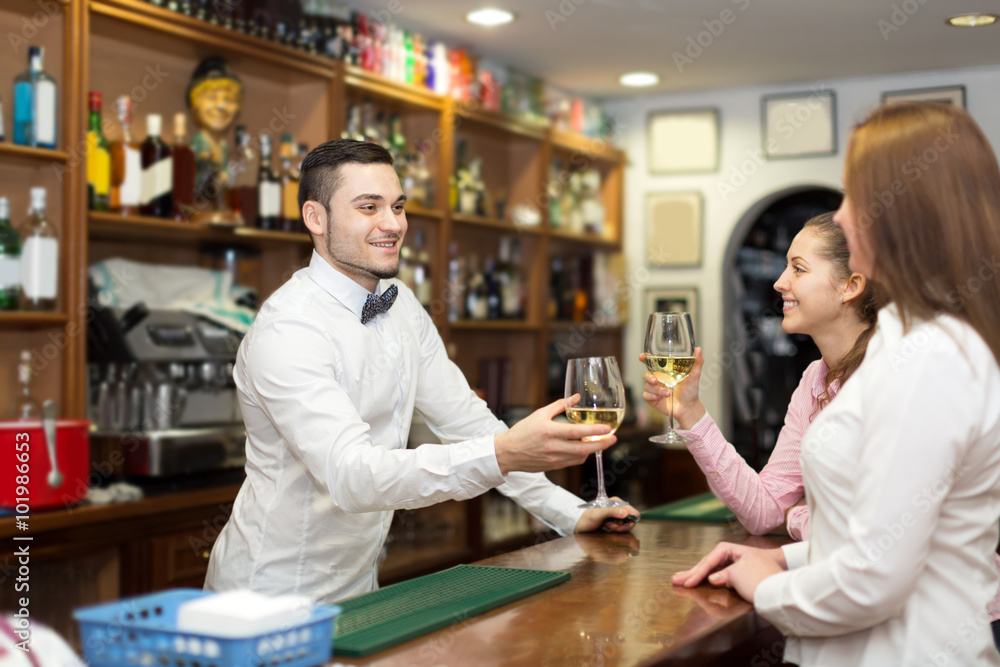 Young bartender and smiling women