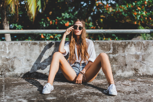 young beautiful girl hippies in sunglasses poses next to an abandoned house photo