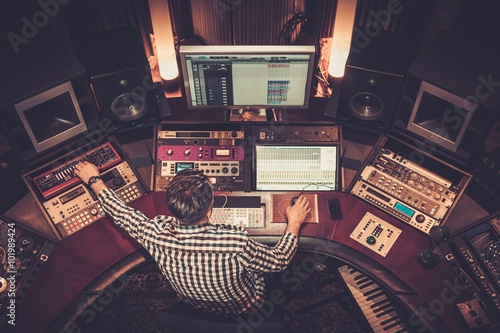 Sound engineer working at mixing panel in the boutique recording studio. photo