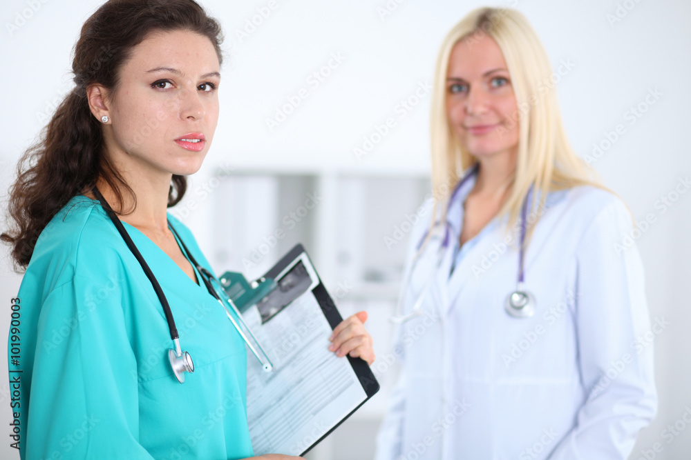 Two confident friendly female doctors sitting at the table and listen to the patient's history . Medical and health care concept Two confident friendly female doctors sitting at the table and listen to the patient's history . Medical and health care concept