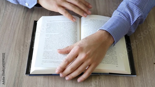 mani che sfogliano le pagine di un libro su un tavolo photo