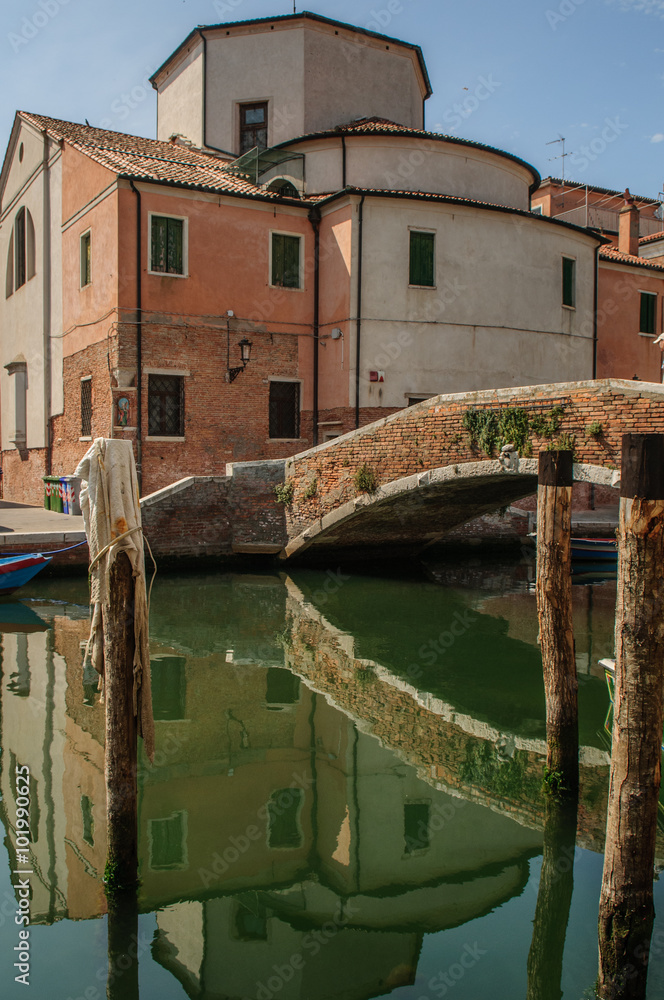 Street view over channel with houses and reflections in Chioggia