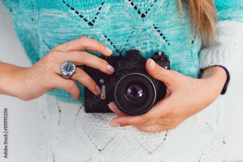 Young sexy blonde woman posing on white wall with professional camera, wearing leater jacket, swag accessorize,hipster outfit , holding vintage camera, Lifestyle portrait bright toned colors.
 photo