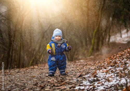 Little boy watching falling snow. Early winter caucasian child portrait.