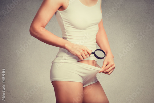 Valokuva attractive slim woman looking with a magnifying glass on her pubic hair on the c