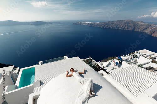 Beautiful brunette bride lying on the terrace in white dress wit