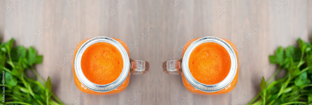 Two Healthy carrot smoothies in a jars on wooden background with parsley. Shallow dof Two Healthy carrot smoothies in a jars on wooden background with parsley. Shallow dof